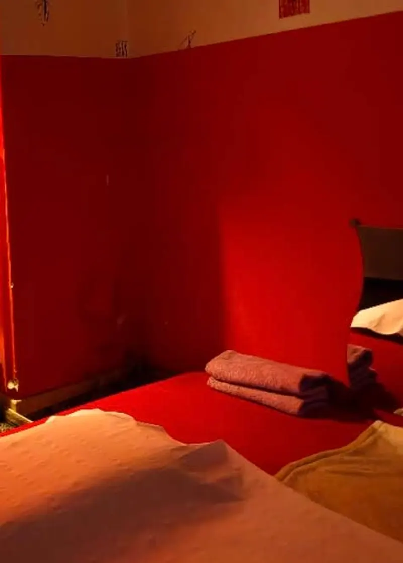 La cabine d’Une Beauté : murs rouges, serviettes pliées, drap clair