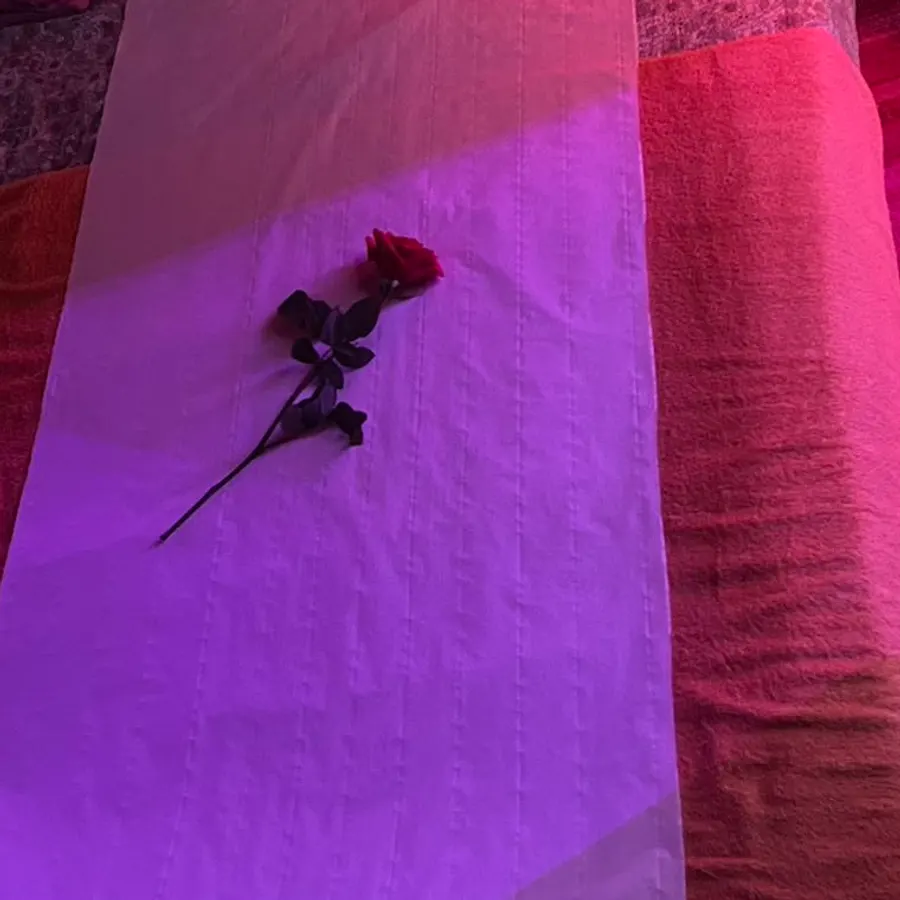 Une rose rouge posée sur le drap blanc de la table de massage, chez Une Beauté